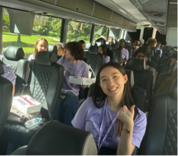 A young woman on a bus full of students gives a thumbs-up