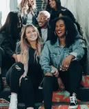 a group of six diverse, joyful women seated on colorfully painted steps